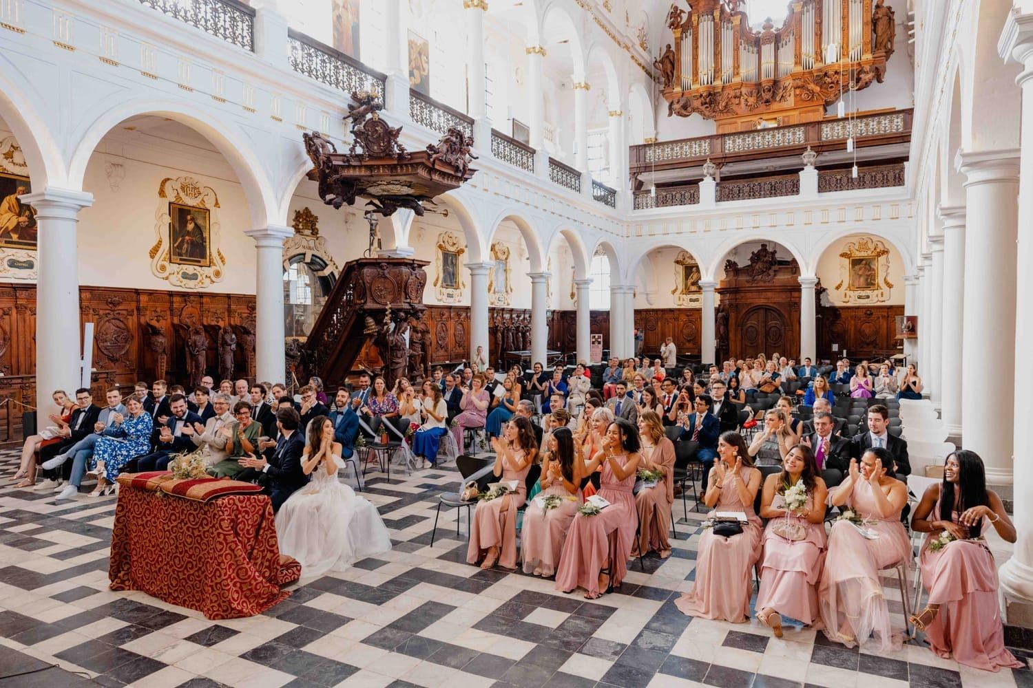 Guests and bridesmaids applauding the couple during the ceremony in a baroque church