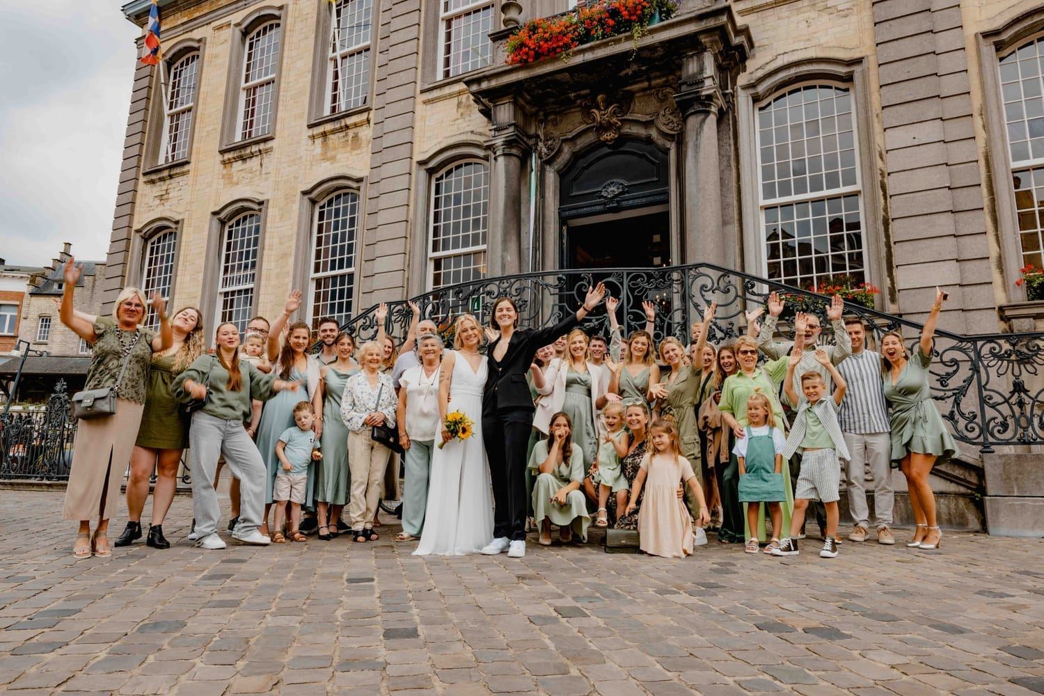 The couple with their family and friends cheering in front of the town hall