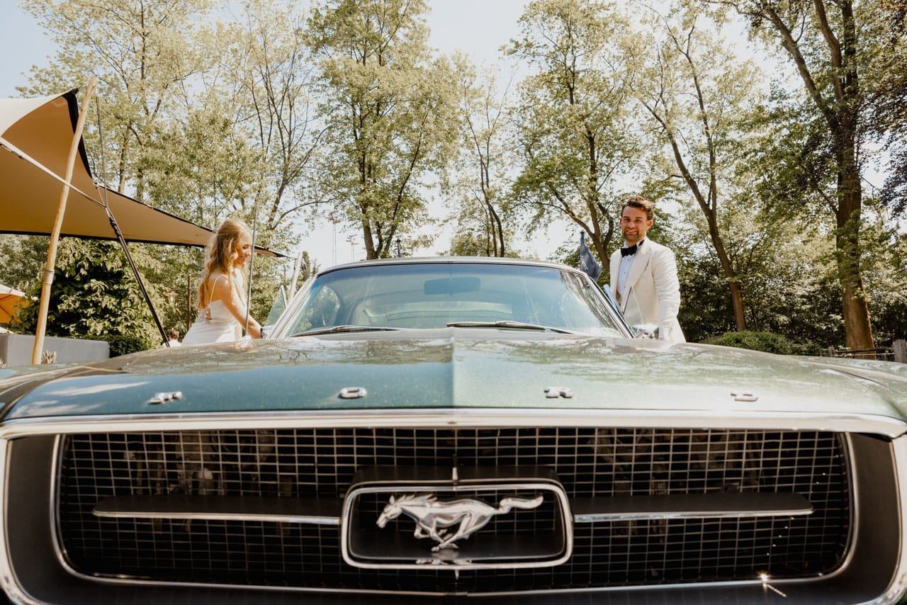 Bride and groom getting into a classic green Mustang