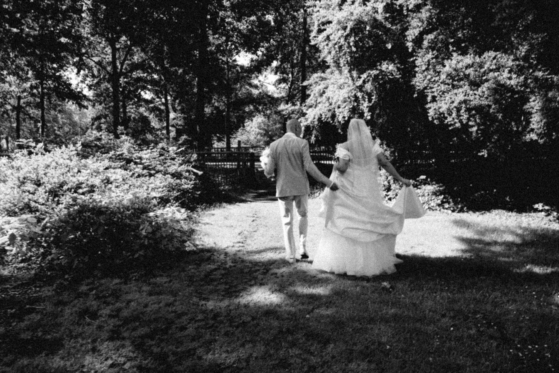 Bride and groom walking away along a garden path, in black and white