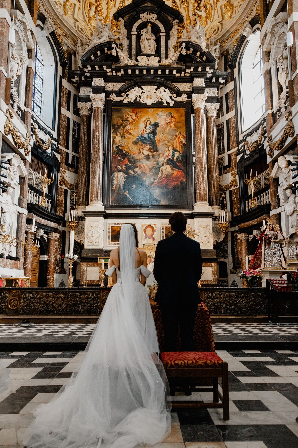 Bride and groom at the altar of a baroque church, seen from behind